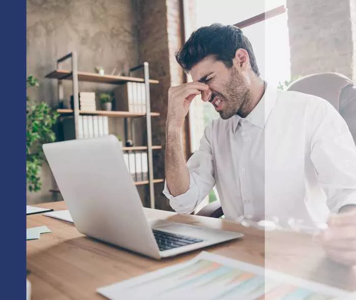 Mann am Computer reibt den schmerzenden Nasenrücken
