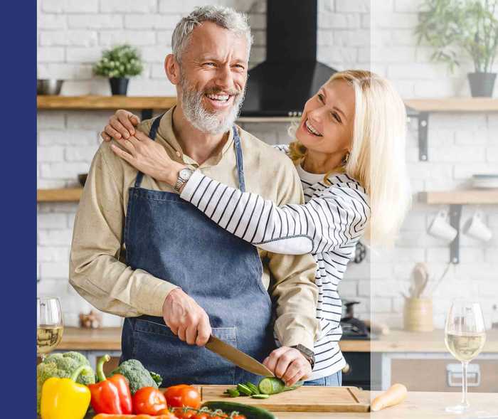 Ehepaar bereitet in der Küche ein Essen mit Gemüse vor.