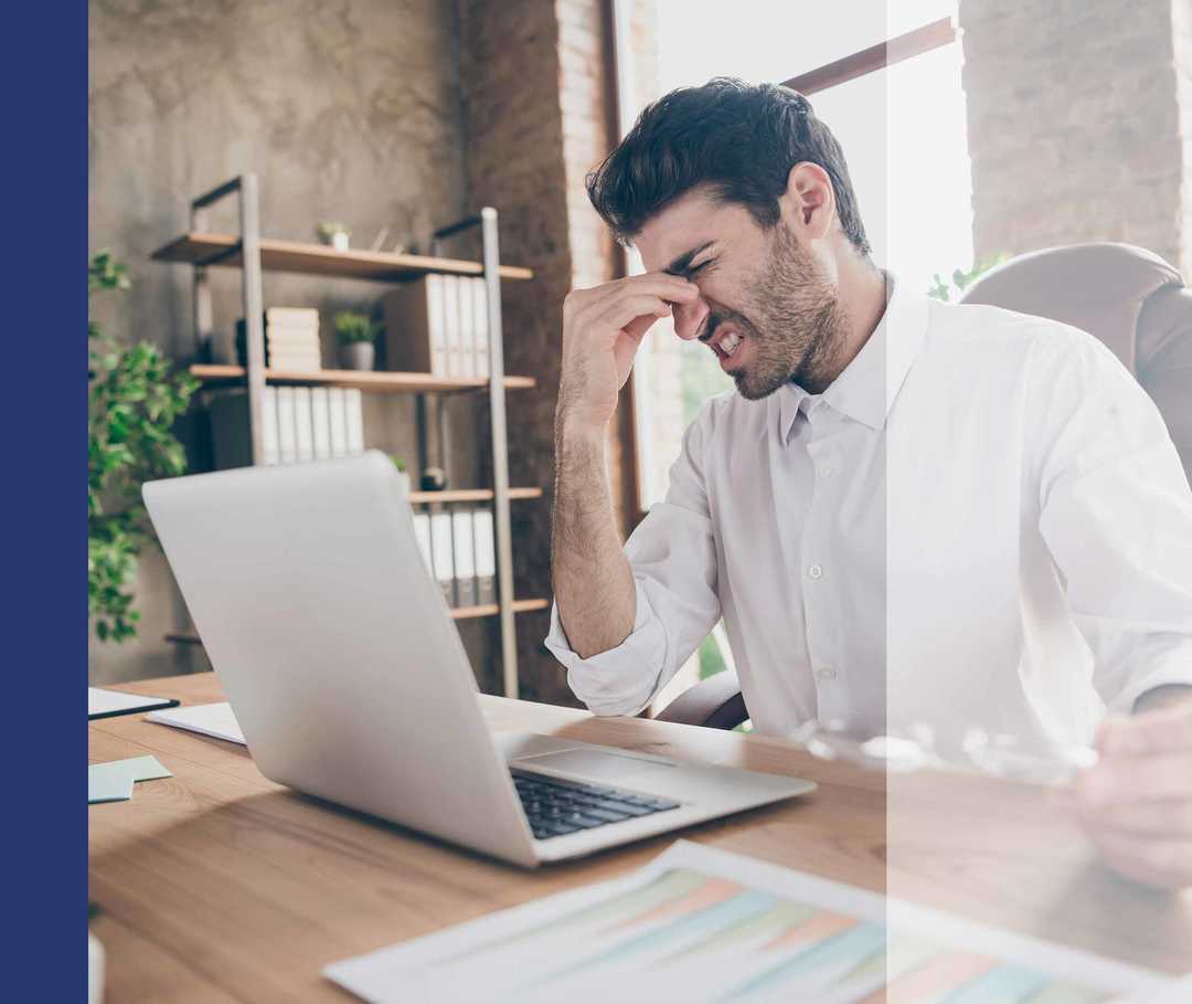 Mann am Computer reibt den schmerzenden Nasenrücken
