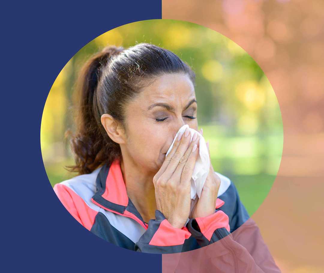 Frau im Freien schnäuzt sich die Nase in ein Taschentuch