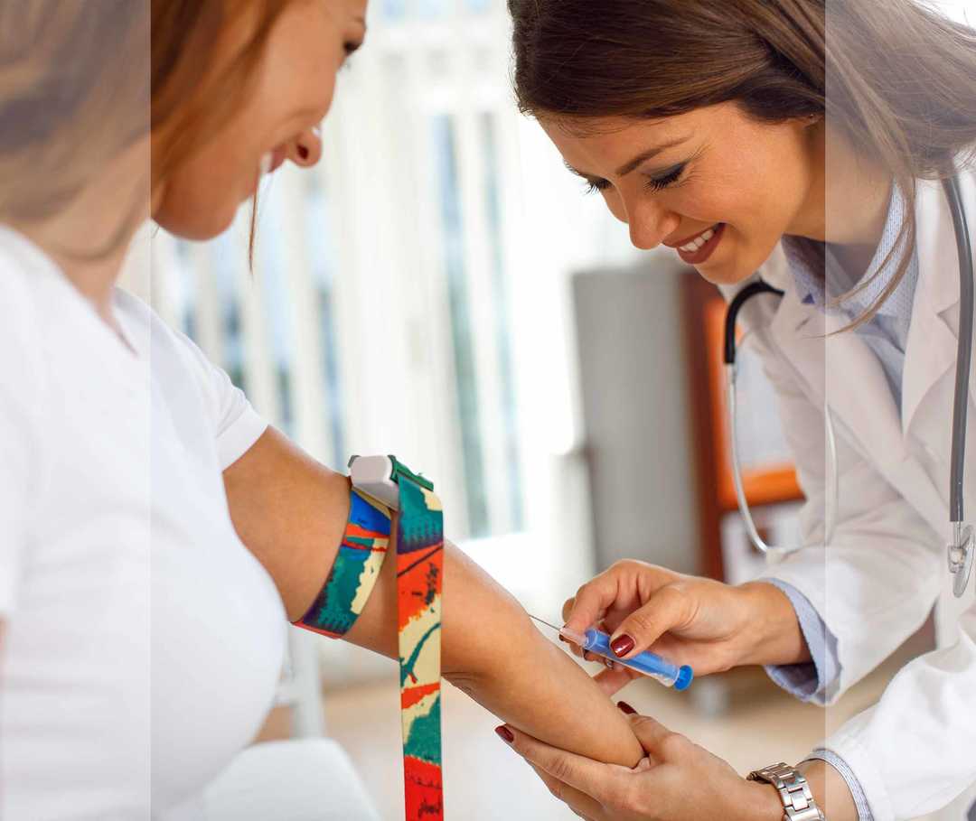 Eine Ärztin nimmt bei einer Patientin Blut ab.