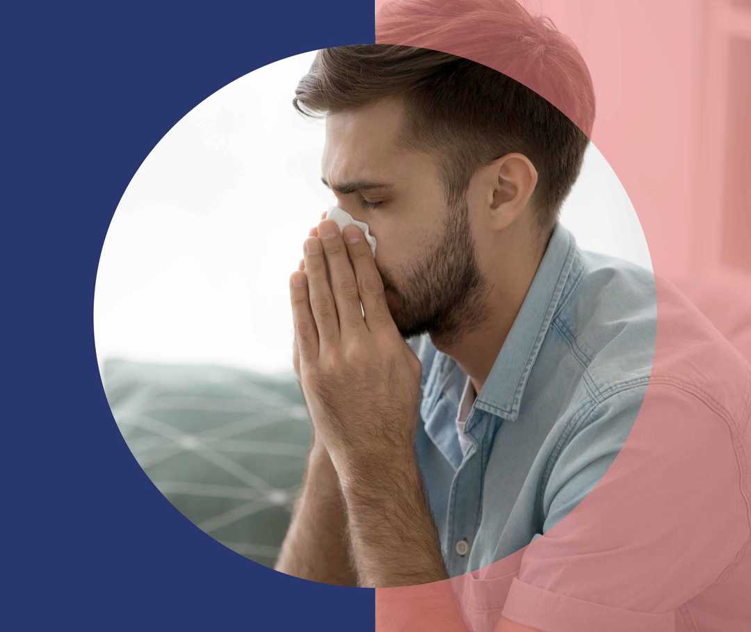 Ein Mann schnäutzt sich die Nase in ein Taschentuch
