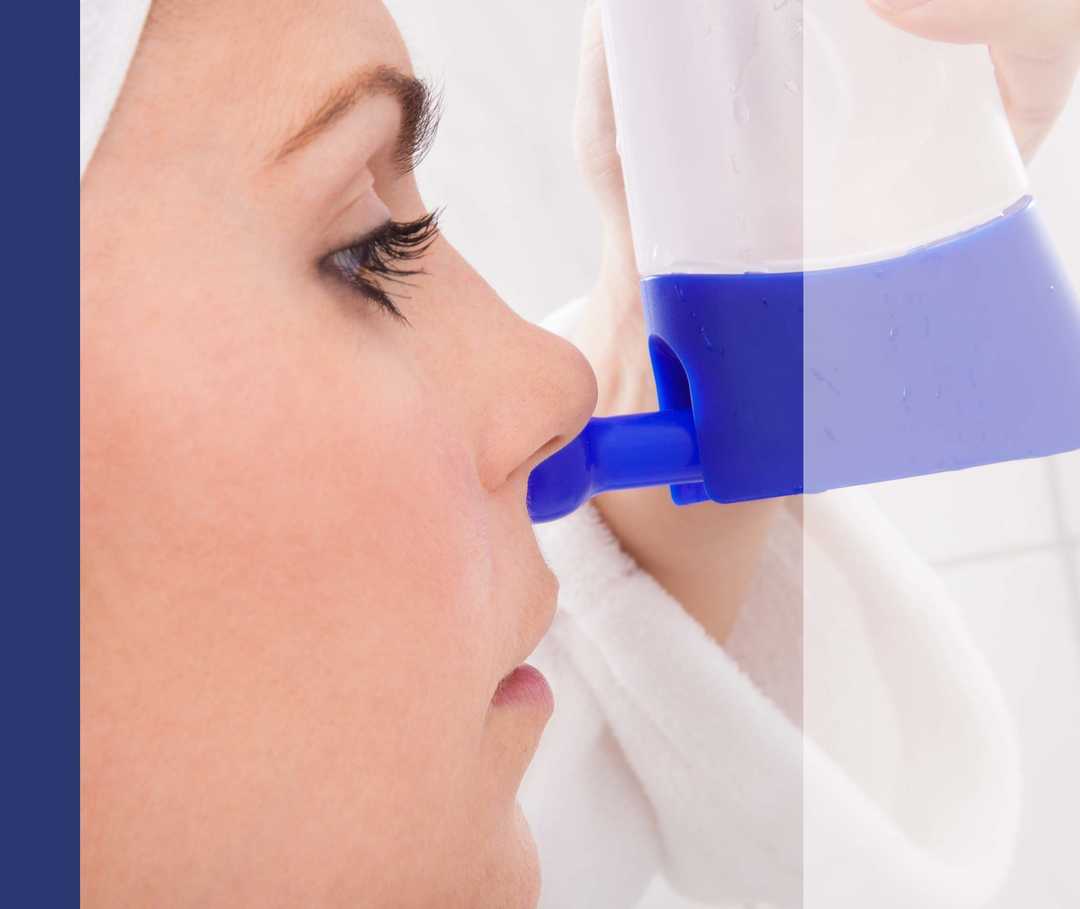 Nasenpolyoen Therapie Linderung Artikelbild 01 Eine Frau lässt mit einer Nasendusche eine Meersalzlösung in ein Nasenloch fliessen.