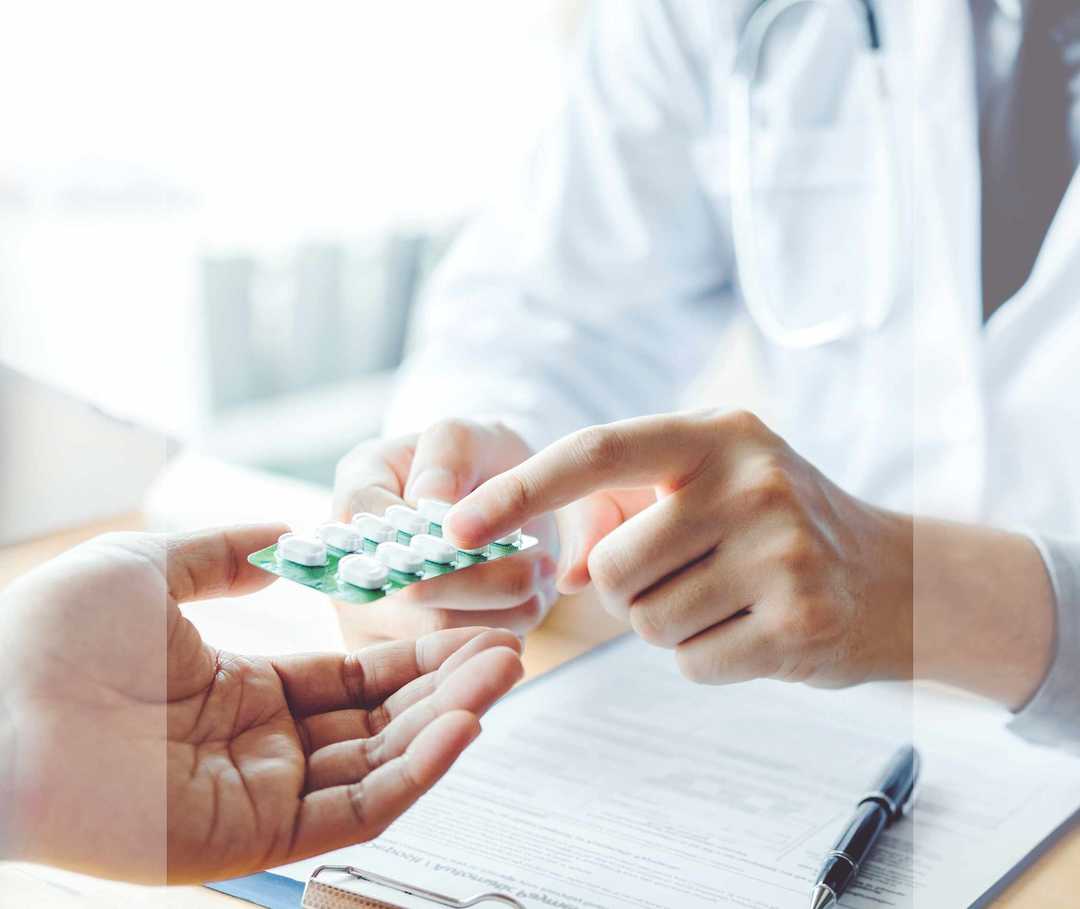 Ein Arzt erläutert seinem Patienten die korrekte Einnahme von Antibiotika-Tabletten. 