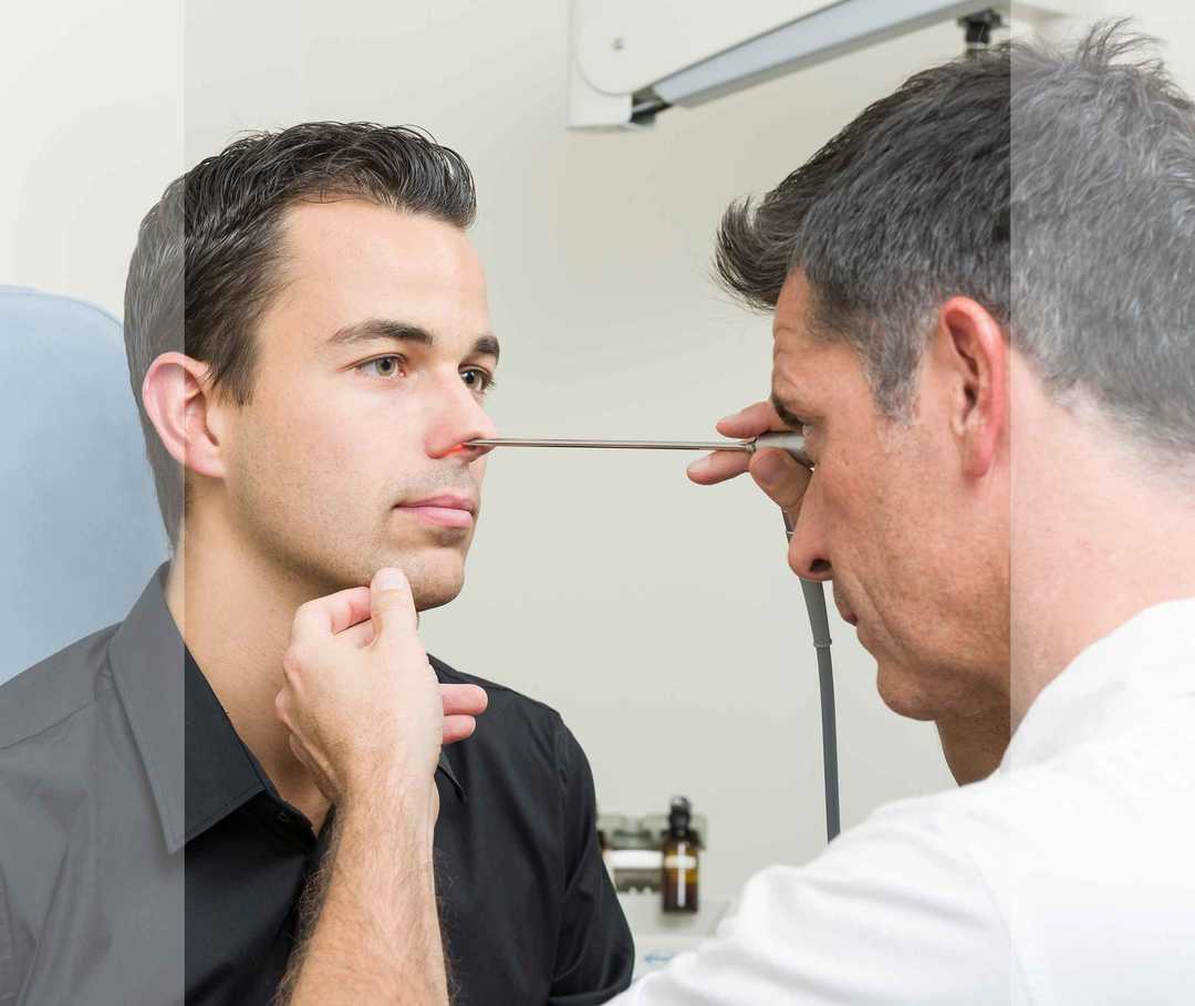 HNO-Arzt untersucht die Nasenhöhle eines Mannes mithilfe eines Endoskops.