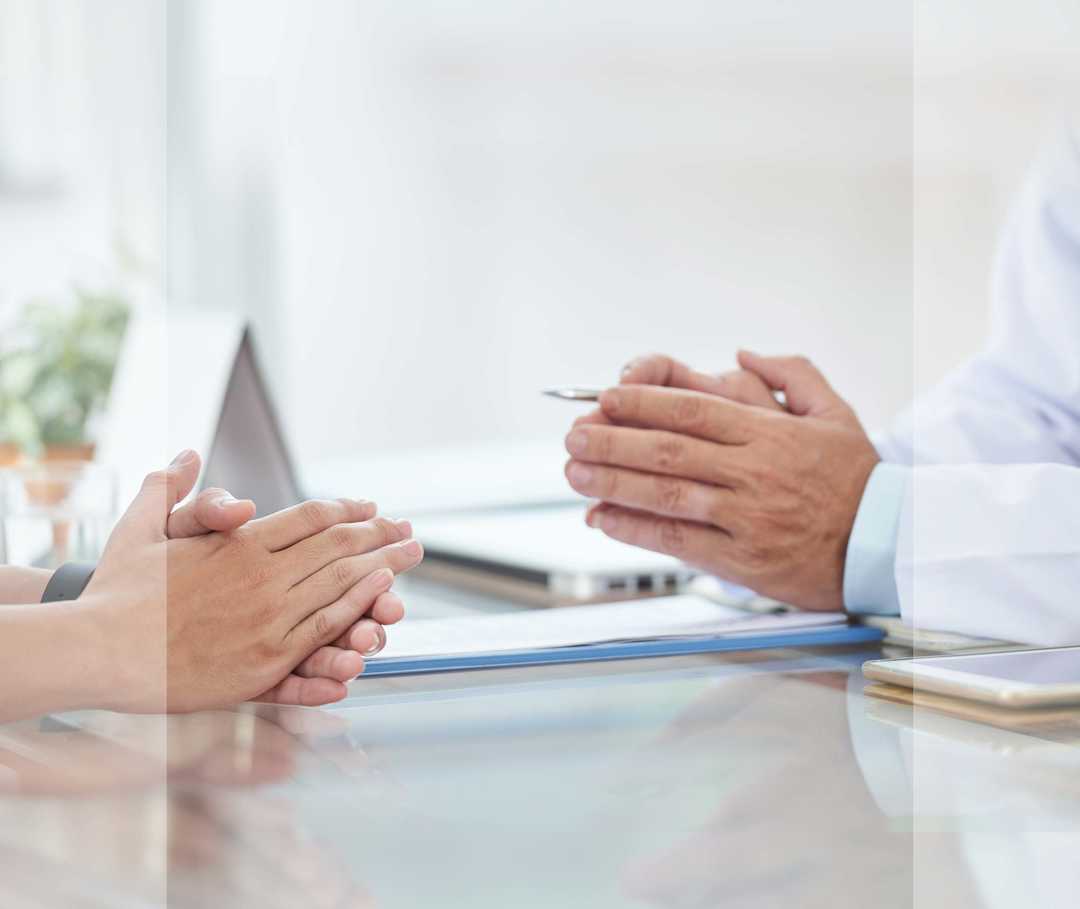 Nasenpolypen Untersuchungen Artikelbild 03 Hände eines Arztes und einer Patientin, die im Gespräch an einem Tisch sitzen.