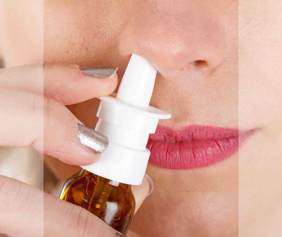 Frau benutzt Nasenspray