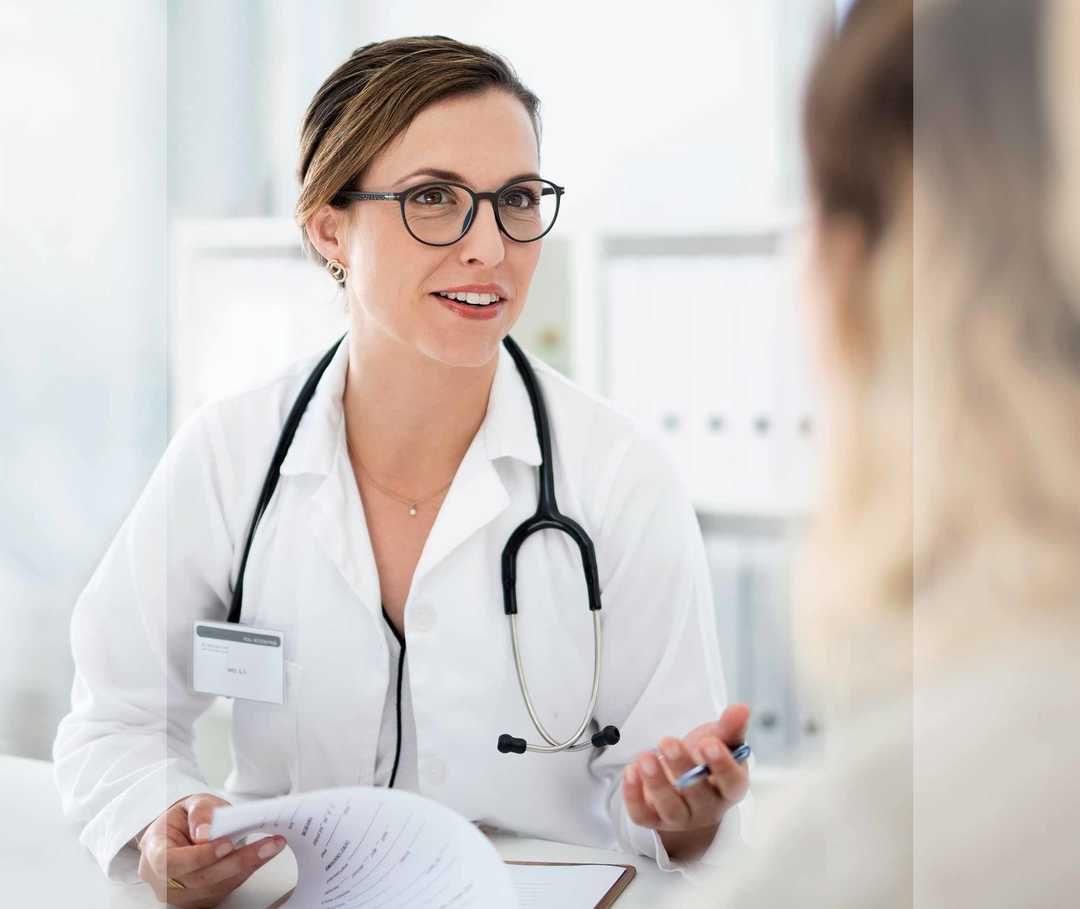 Nasenpolypen-info.de: Differenzialdiagnose Junge Ärztin mit Brille und Stethoskop spricht mit Patientin.